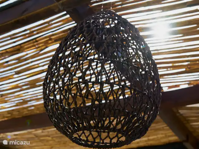 Casa Yavari en España, Costa Blanca, Pedreguer  - villa Vista desde la puerta principal de Casa Yavari
Desde la puerta principal se mira hacia la puerta superior. A la izquierda, se puede ver la pérgola de estilo ibicenco con dos lámparas negras ibicencas, rodeadas de exuberantes flores. También es visible la barbacoa, perfectamente integrada en este atractivo espacio exterior.