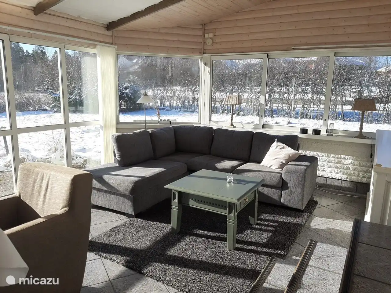 Geräumiger Wintergarten mit Glas rundum und einer Schiebetür.