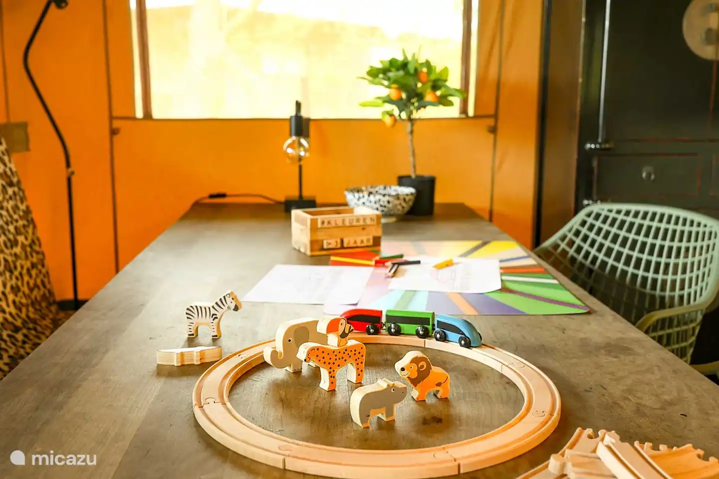 Houten treinbaan en kleurpotloden liggen in de glampingtent