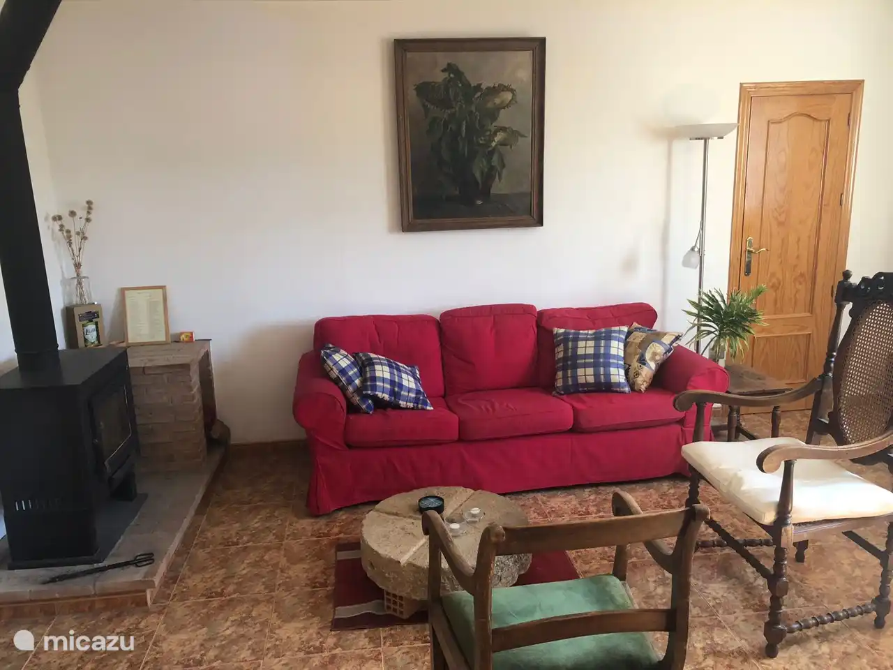 Wohnzimmer mit Holzkamin und einem originalen Olivenmühlenstein als Couchtisch. Die Tür auf dem Foto führt zu einem der Schlafzimmer.