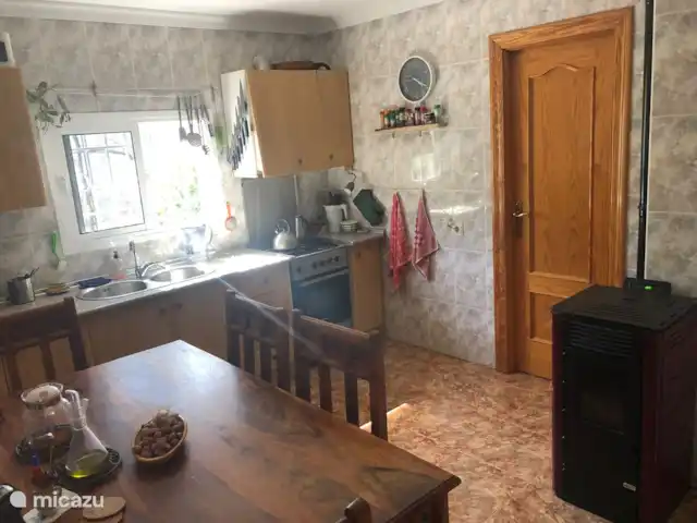 Casa de los Arboles - Iznájar | Espagne, Andalousie, Iznajar - maison de vacances Cuisine avec table à manger et 4 chaises, poêle à pellets et accès au garde-manger. Il y a aussi un grand réfrigérateur avec un compartiment congélateur.