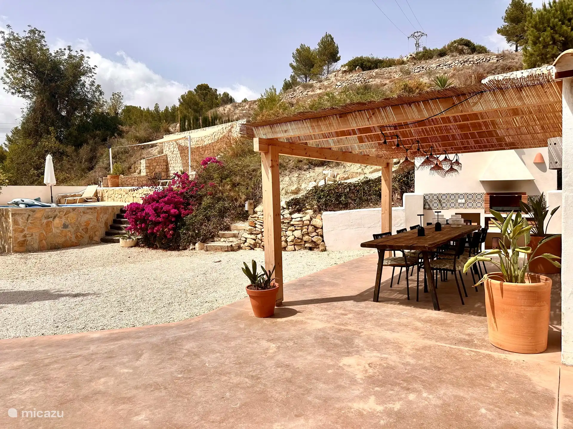 La cuisine extérieure avec coin repas et la piscine privée. Si vous montez les escaliers, vous arrivez à une autre terrasse avec vue sur la mer et chaise suspendue