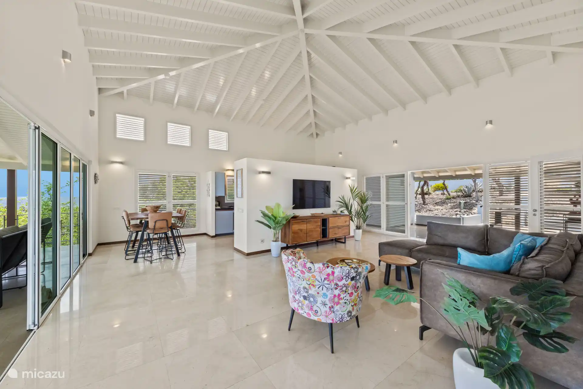 Das offene, windgekühlte Wohnzimmer verfügt über einen Esstisch, ein bequemes Lounge-Sofa, einen großen TV-Schrank (mit Apple TV Receiver) und ein kleines Homeoffice mit Highspeed-Internet.