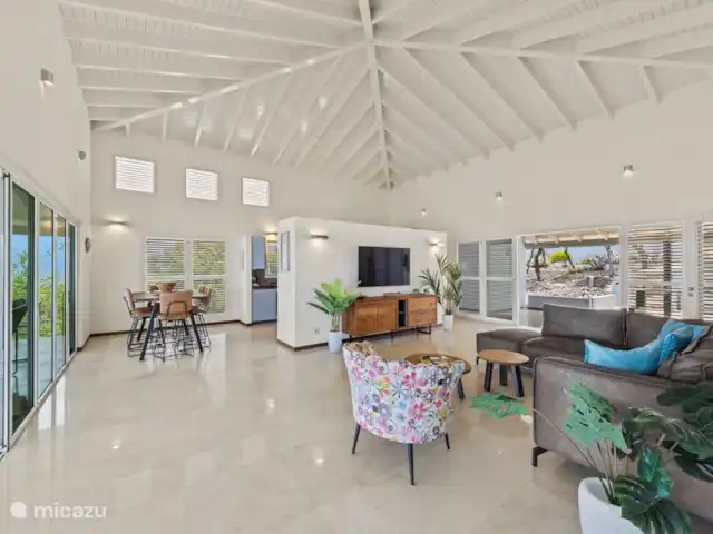 Villa Blue Oasis huren in Curaçao, Banda Abou (west), Coral Estate, Rif St.Marie - villa De open, windgekoelde woonkamer heeft een eettafel, een comfortabele loungebank, een groot tv-meubel (met Apple TV-ontvanger) en een klein thuiskantoor met snel internet.