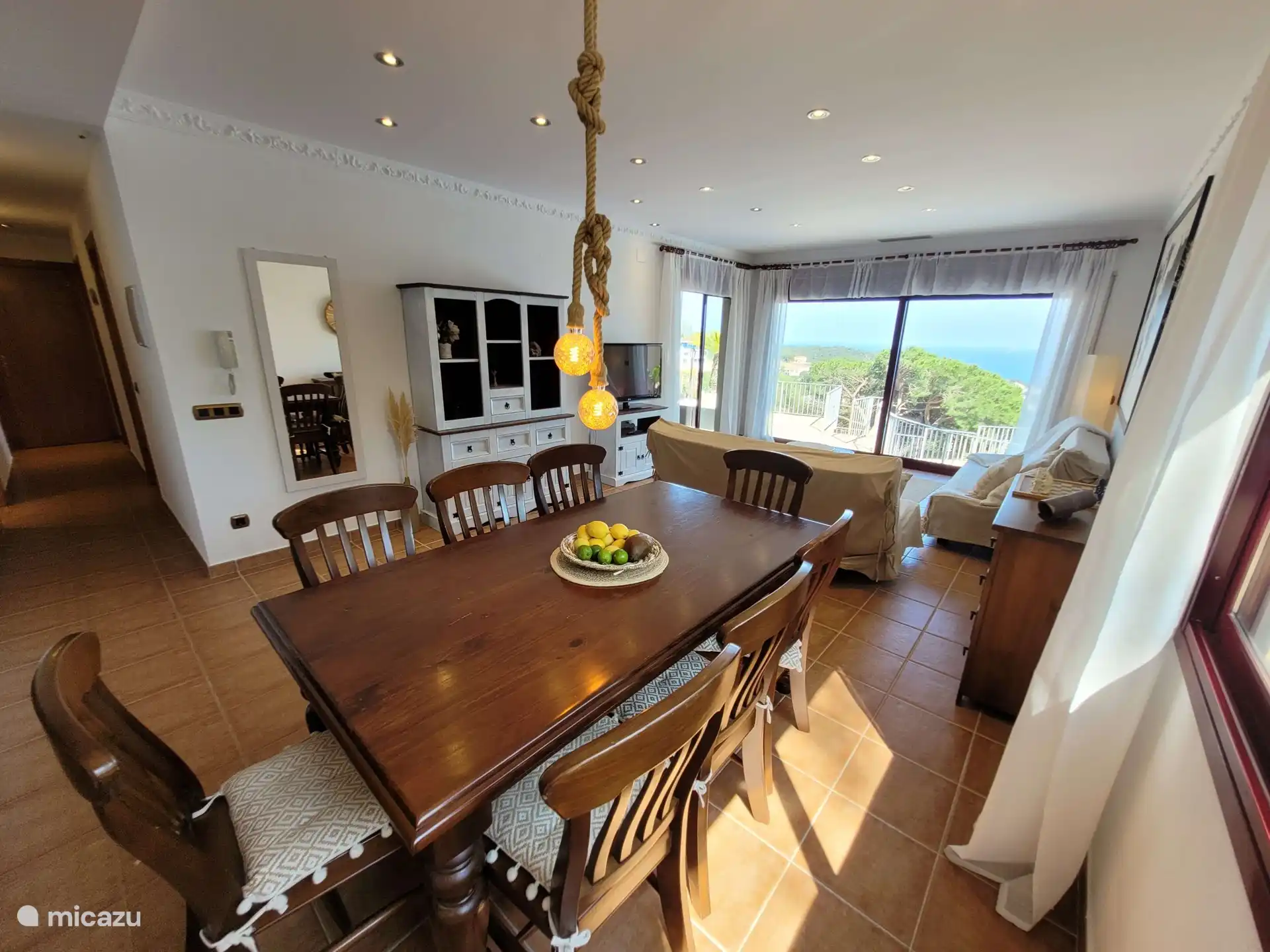 Salon spacieux avec table à manger, on peut clairement voir l’emplacement et à gauche le couloir menant aux chambres