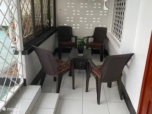 Location de Vacances Suriname, Paramaribo, Paramaribo, maison de vacances - Mendes House Appartement au rez-de-chaussée balcon avec chaises et ventilateur. en 2024