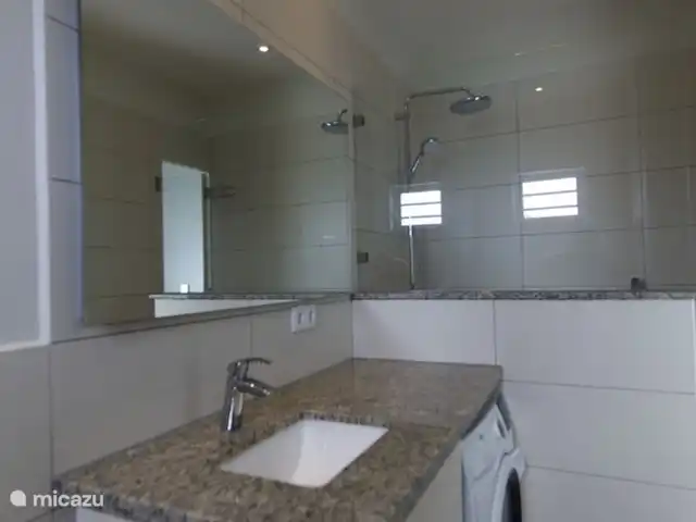Location de Vacances Curaçao, Curaçao-Centre, Blue Bay, appartement - Casa Rosa Curaçao salle de bain avec lavabo, WC, machine à laver et grande douche à l'italienne avec pomme de douche pluie