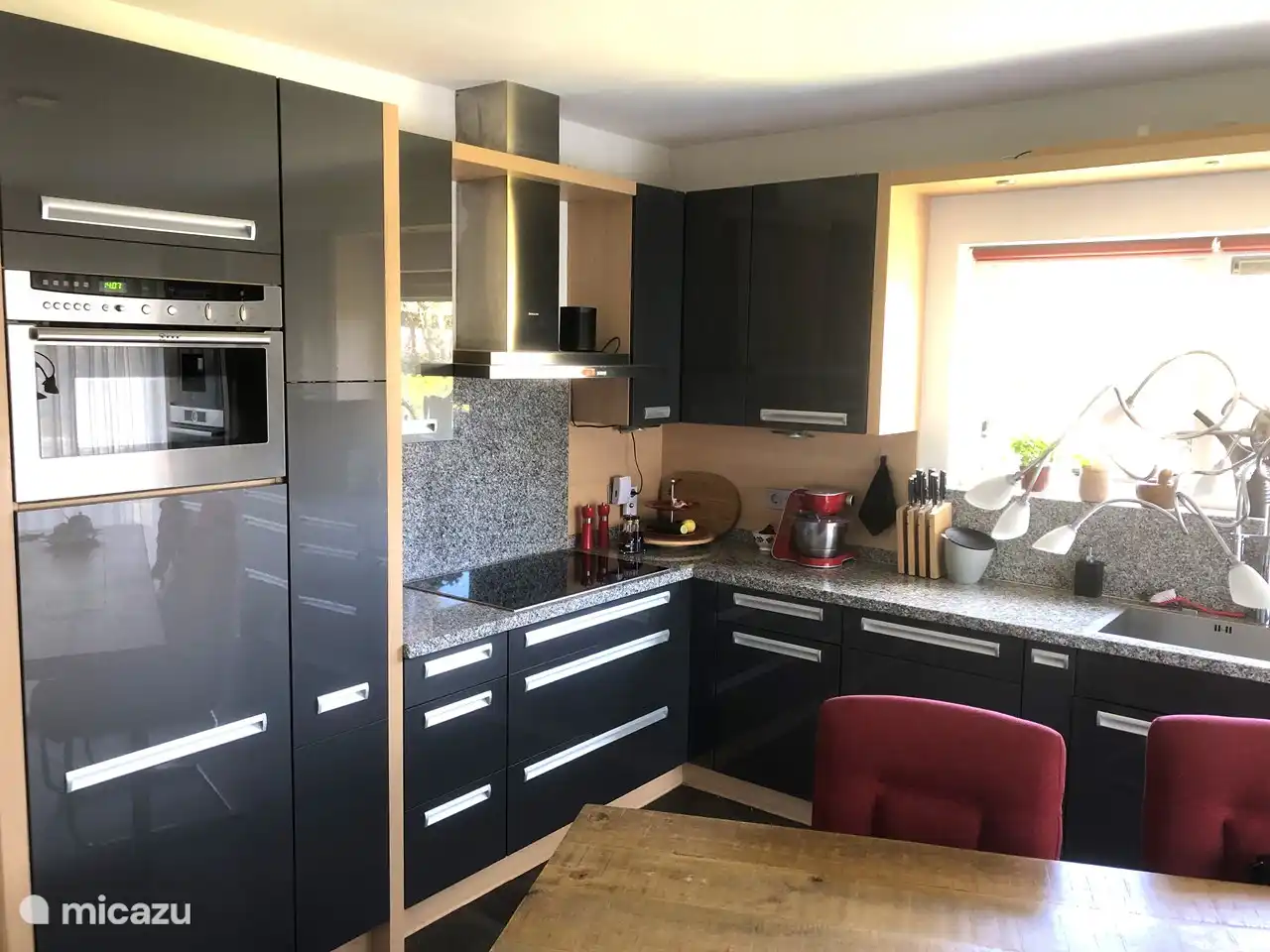 Küche mit Induktionskochfeld und großem Kühlschrank und Kombi-Backofen/Mikrowelle.