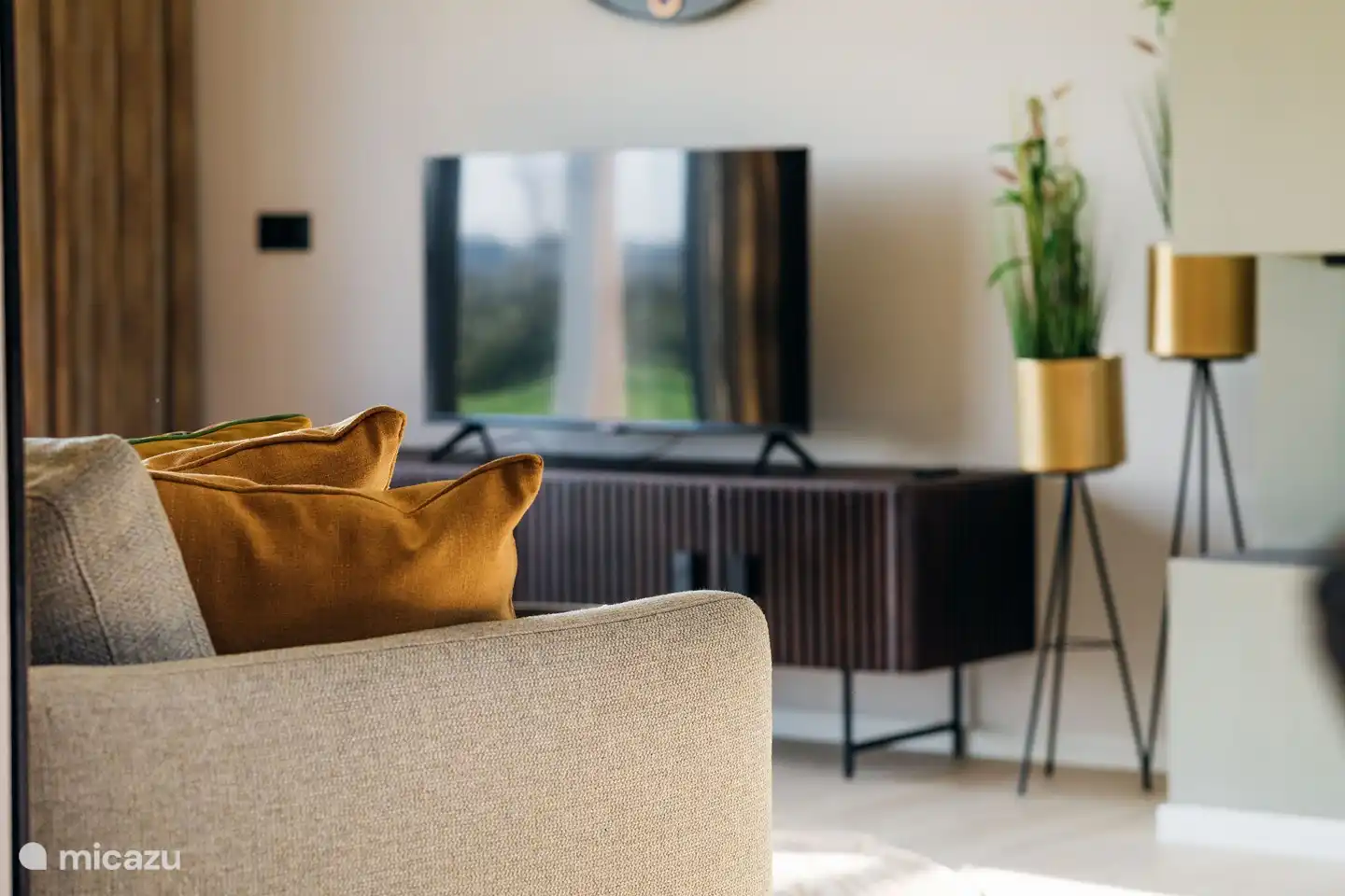 Sfeervolle woonkamer met open haard en openslaande tuindeuren en een grote zithoek voorzien van een Smart TV.