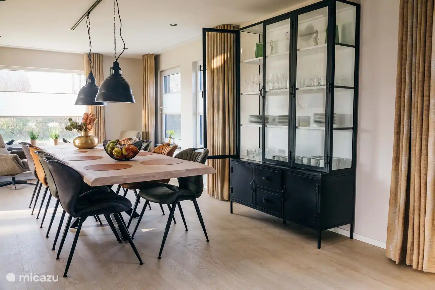 Sfeervolle woonkamer met open haard en openslaande tuindeuren en een grote zithoek voorzien van een Smart TV.