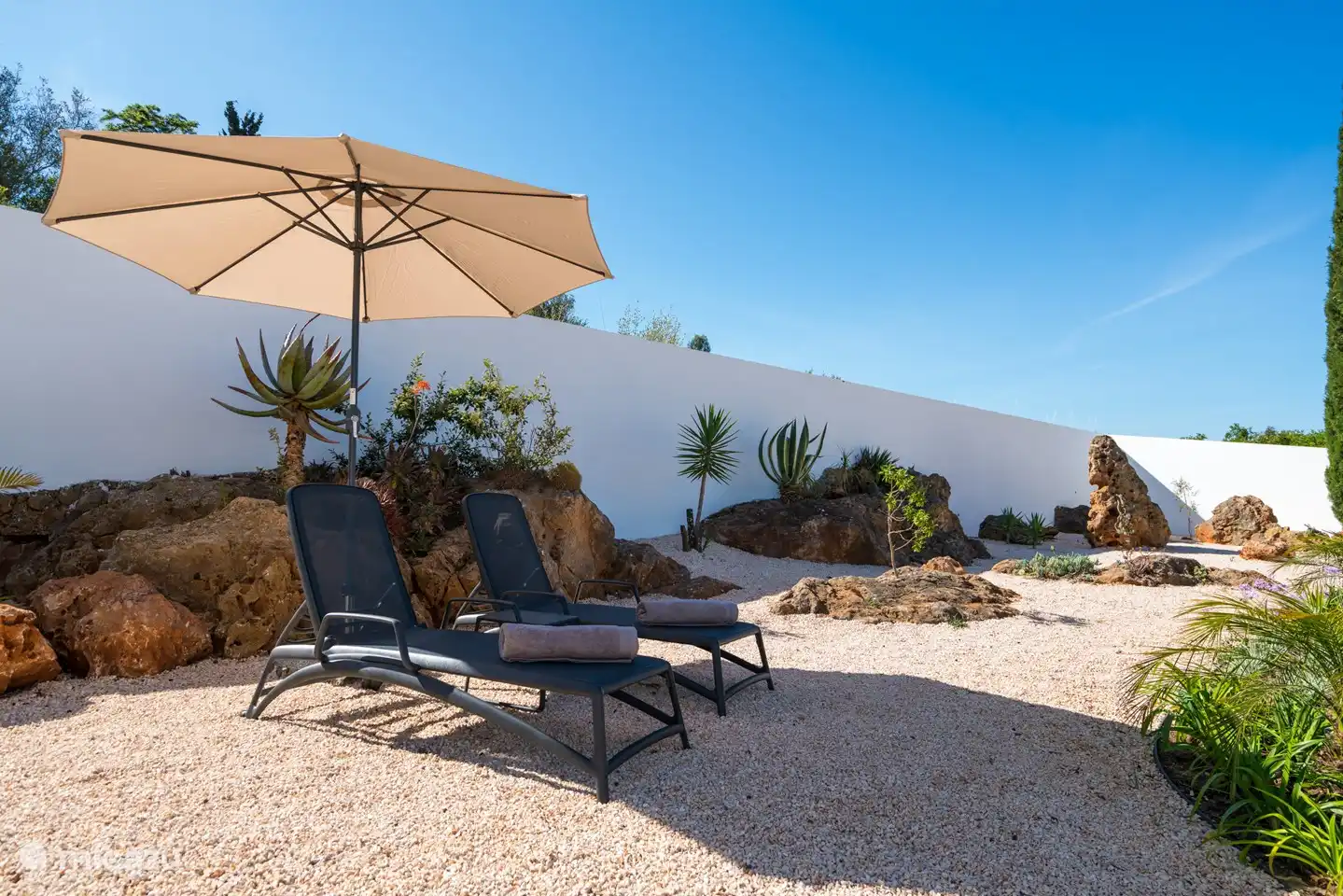 2 schöne Sonnenliegen zwischen den Felsen im Garten.