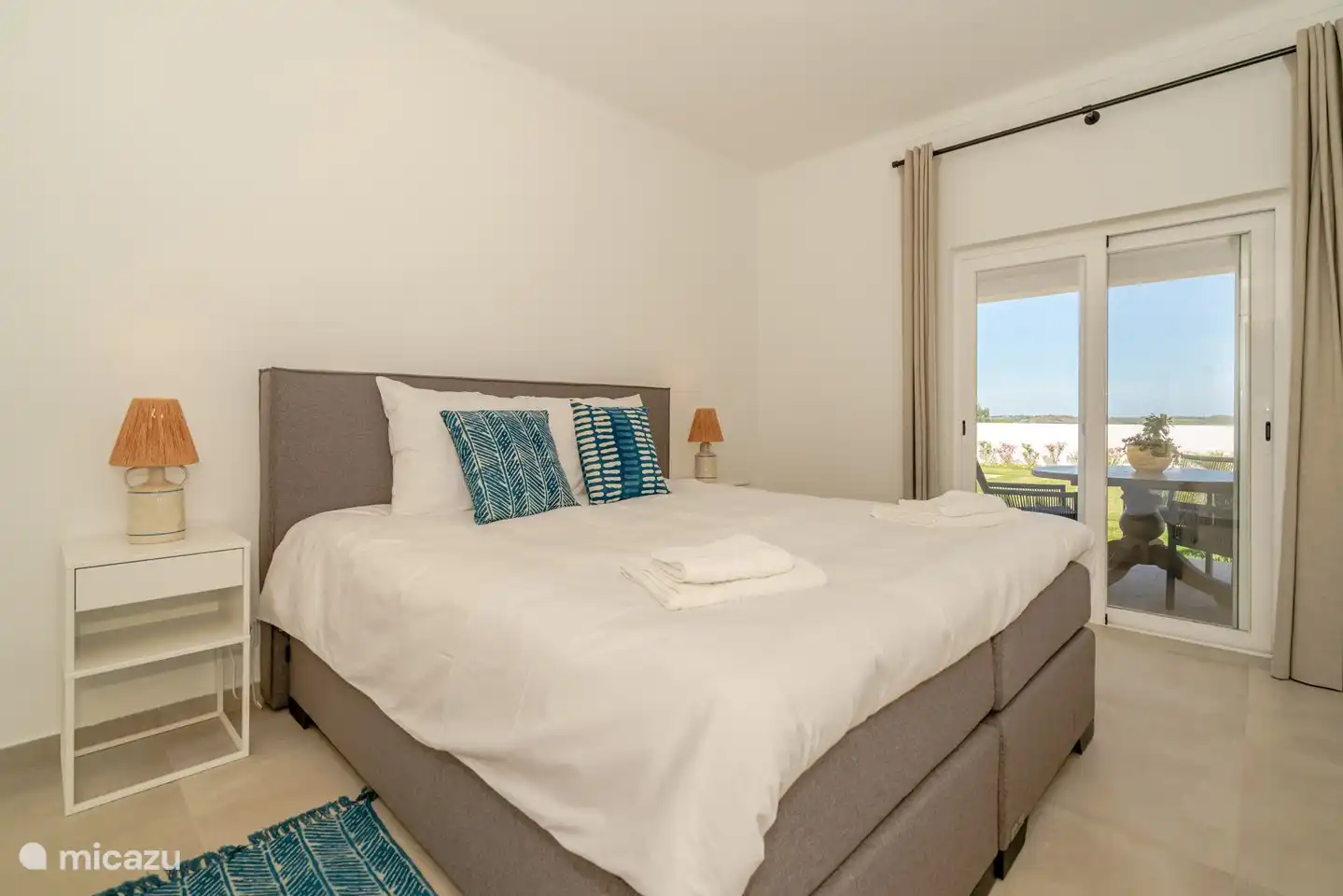 2-Personen-Schlafzimmer auf der Gartenseite mit Schiebetüren zu einer privaten Terrasse im Schatten.