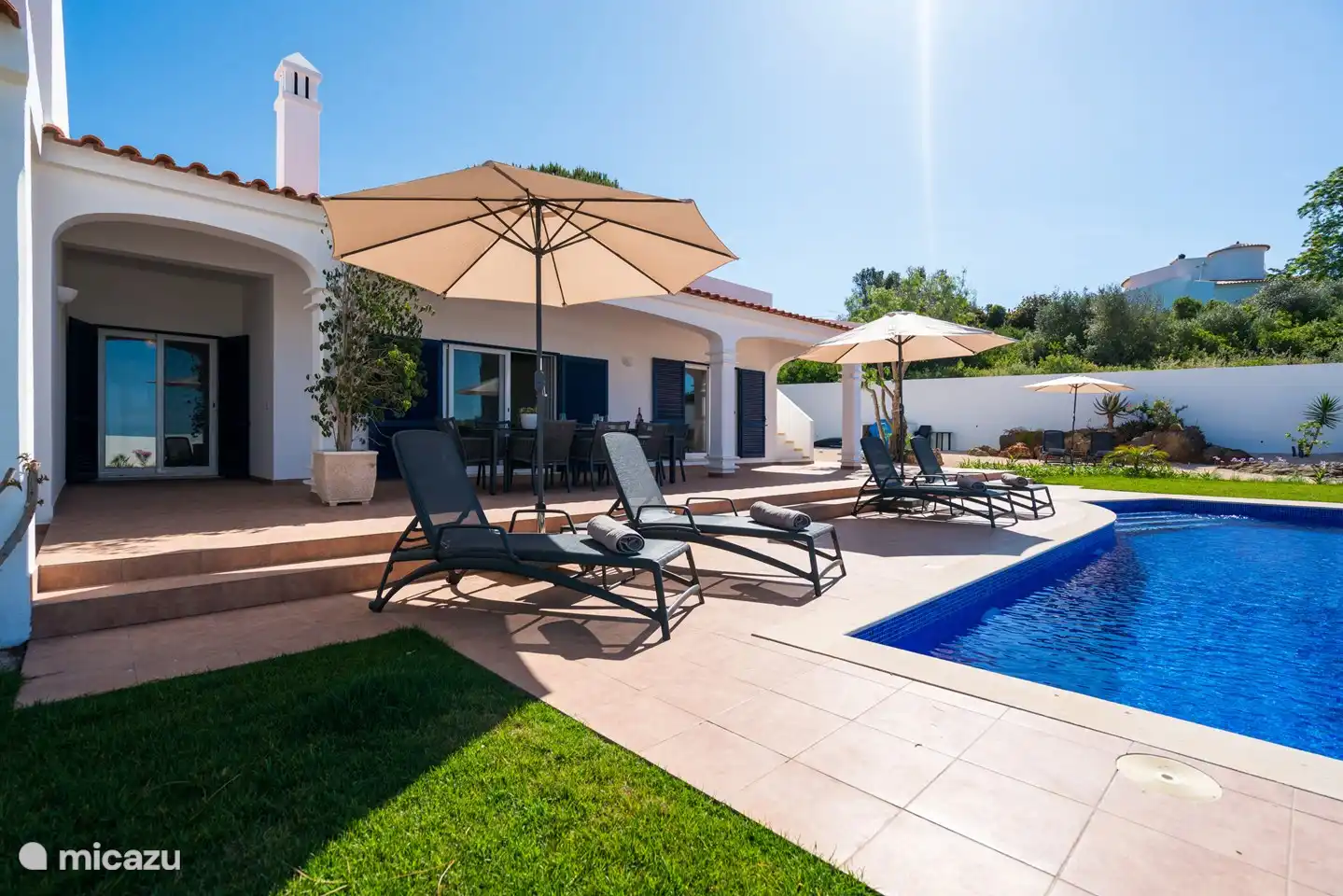 Viele Sonnenliegen im Garten entlang des Pools. Es gibt genug Privatsphäre.