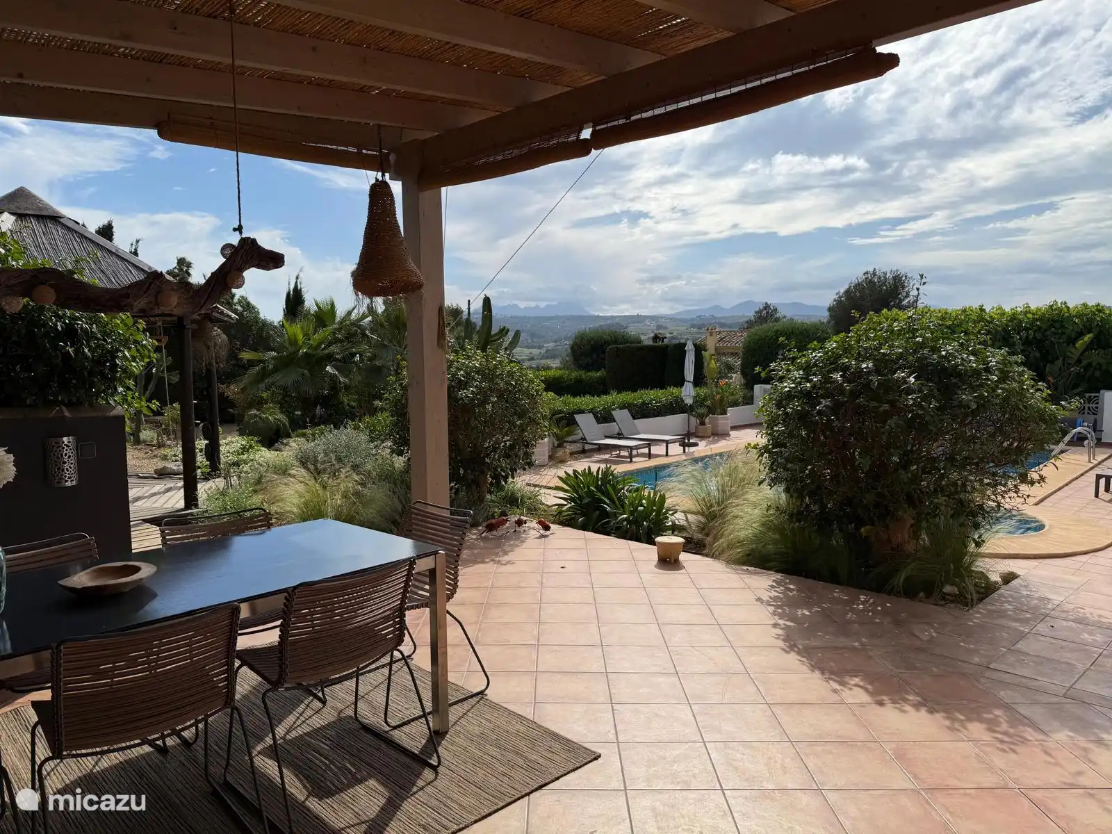 the view from 1 of the covered terraces on the pool with the mountains in the background