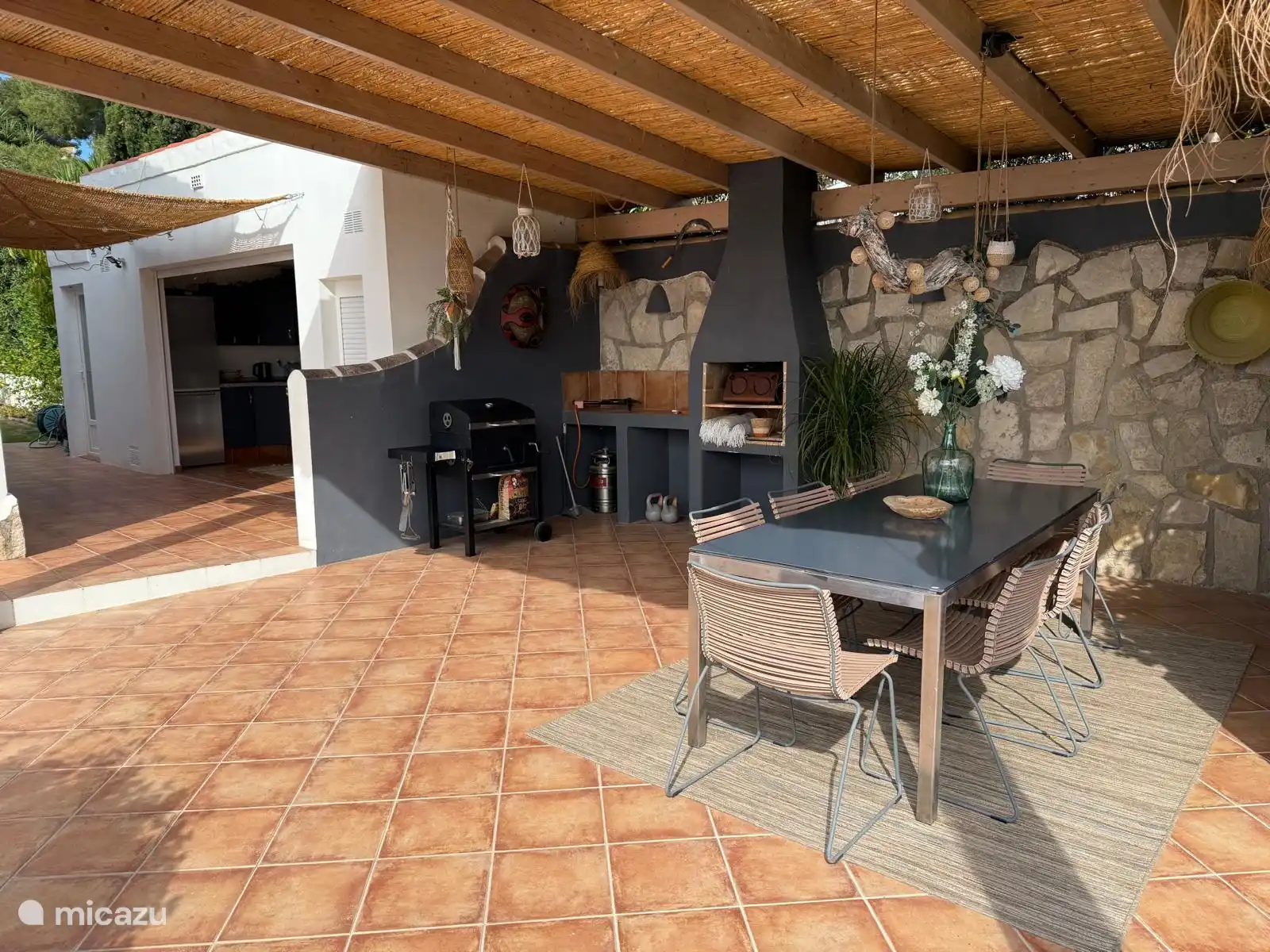 The covered terrace with dining table, 8 chairs, barcbecue with coal is adjacent to the outdoor kitchen. In a separate area there is also a toilet and a washing machine