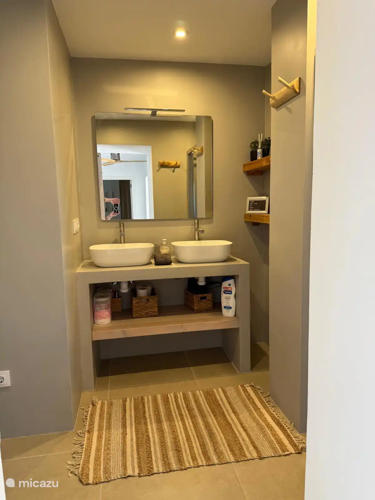 The bathroom in the apartment has a toilet, double sink and a shower