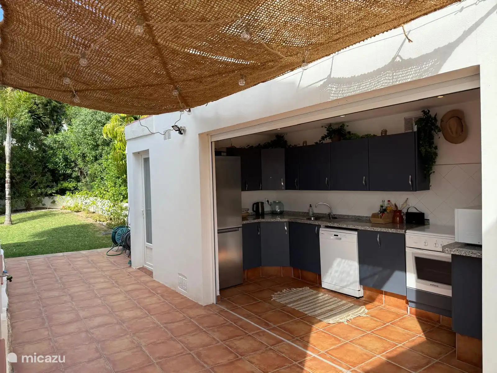The outdoor kitchen is adjacent to the large covered terrace and is equipped with a fridge with freezer compartments, dishwasher and gas stove