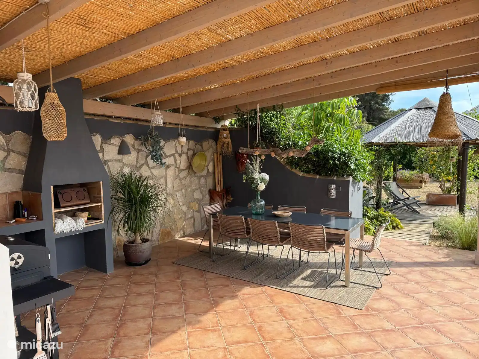 the covered terrace next to the outdoor kitchen by the pool