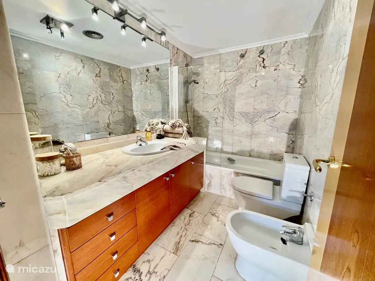 Bathroom with a large bath, toilet, bidet, large sink and ample storage space.
