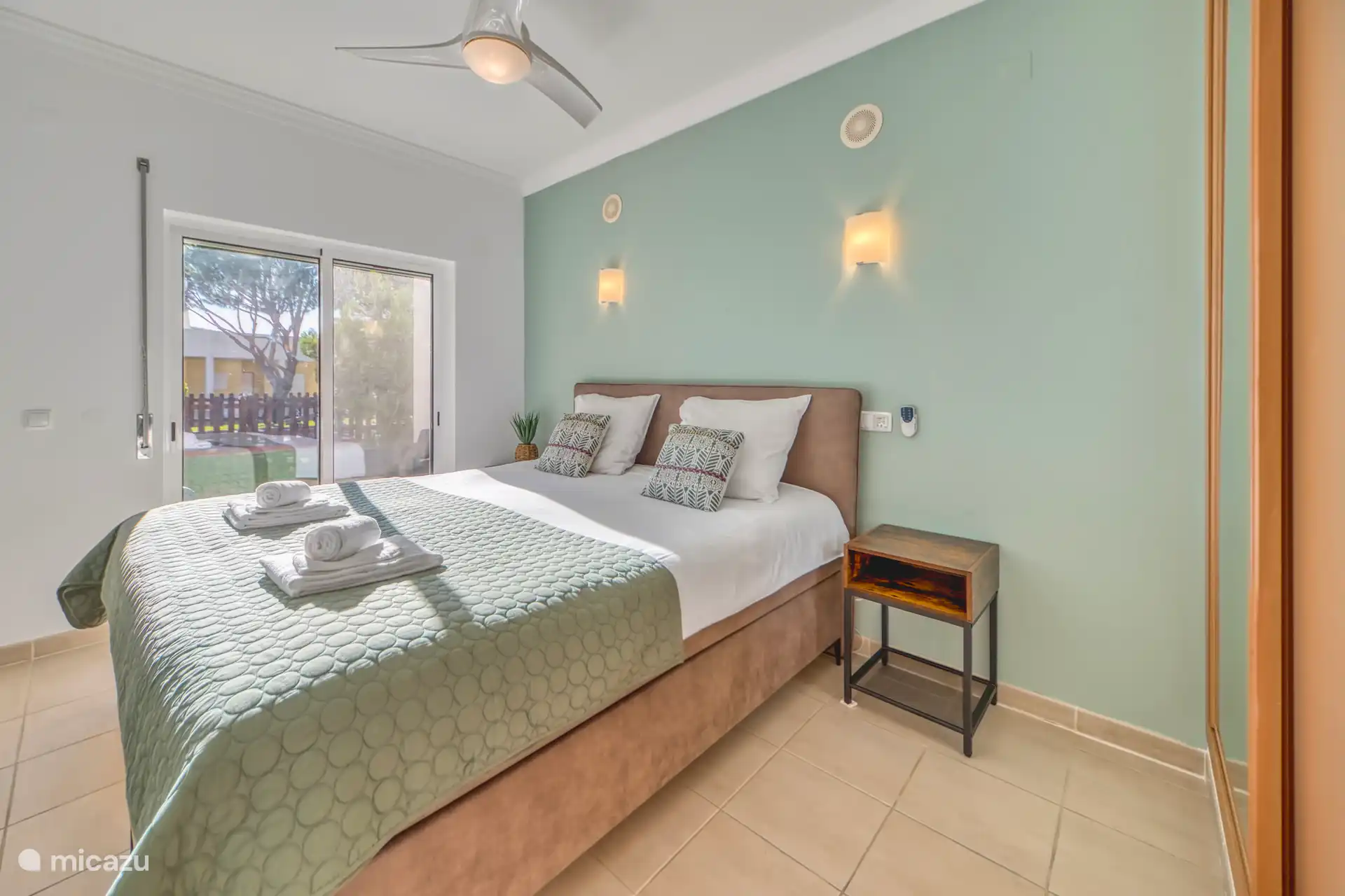 Ruime slaapkamer met een kingsize bed, uitzicht op het terras. 