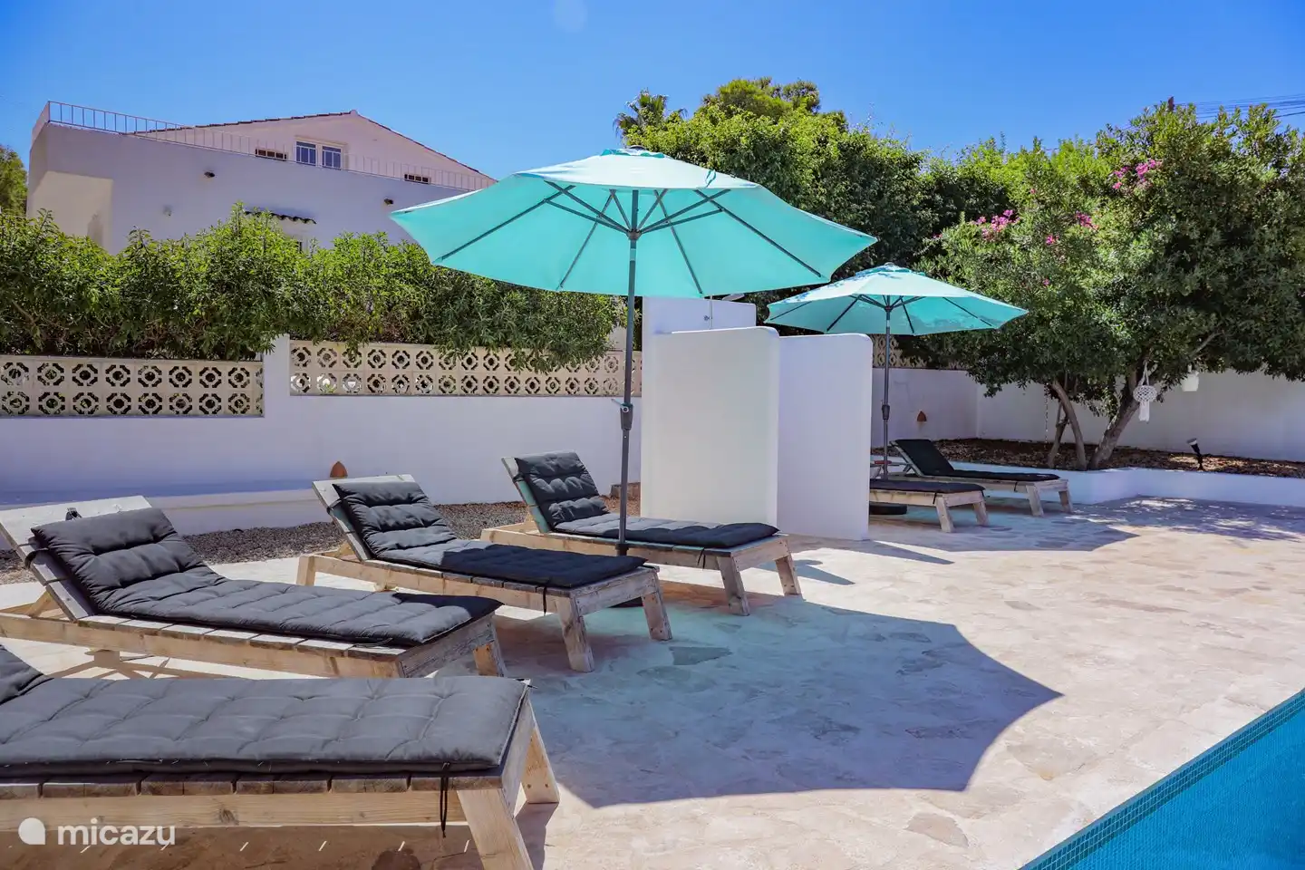 Geräumiger privater Swimmingpool, umgeben von Liegestühlen und Sonnenschirmen.