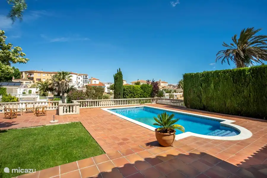 Large garden with spacious swimming pool, sunbeds, lounge set and a view of a wide canal.