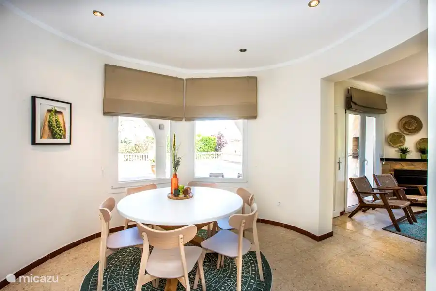 The cozy dining area with red table and 6 chairs, adjacent to the open kitchen.