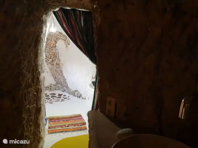 Casa cueva creativa con jacuzzi en España, Andalucía, Gorafé - casa cueva El baño especial consta de 2 habitaciones una detrás de la otra. La habitación trasera, con luz natural, tiene una ducha de efecto lluvia y un jacuzzi y está decorada de forma creativa con conchas y escalones rojos de la zona.