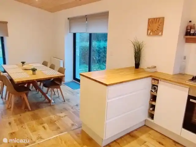 Eclusa de Guendol en Francia, Bretaña, Plouguernevel - casa vacacional amplia cocina moderna abierta con mesa de comedor y acceso a la terraza sur a través de una ventana corredera