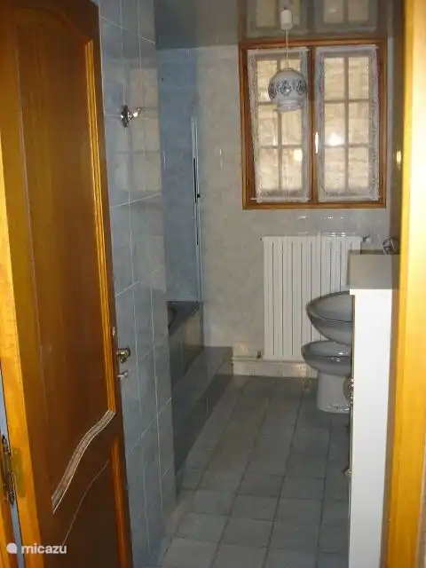 Badezimmer 1 im Erdgeschoss mit Badewanne/Dusche und Waschbecken. Separates WC im Flur