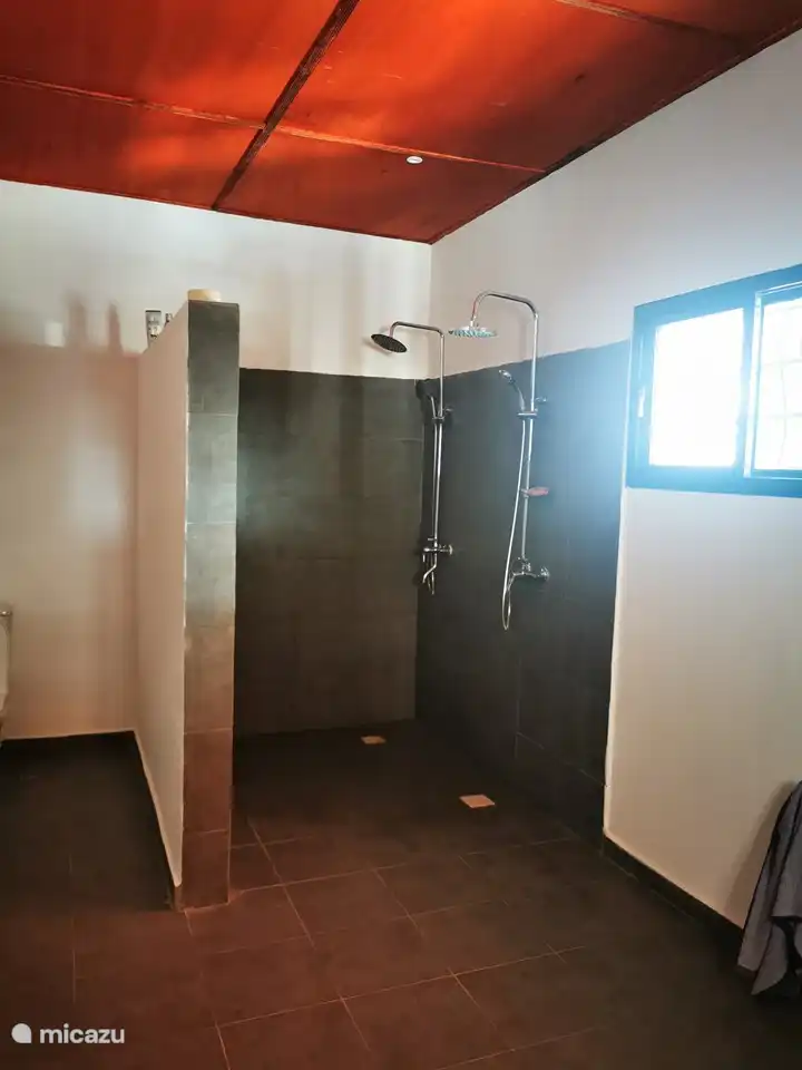 Das Badezimmer des Hauptschlafzimmers mit Doppeldusche und Waschbecken und Möbeln. Hier befindet sich auch die Waschmaschine