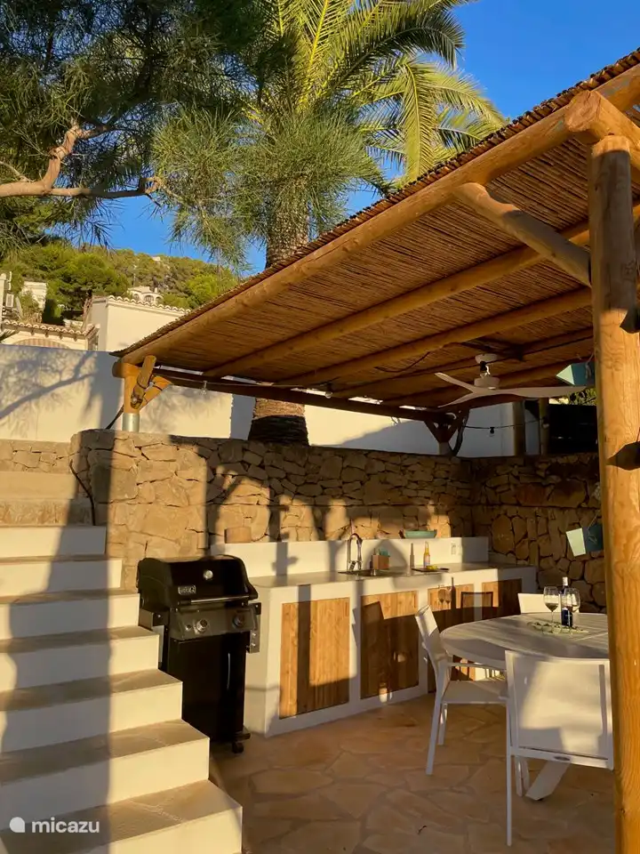 The outdoor kitchen is a pleasant place to be; in the shade during the day and at sunset in the evening. The ceiling fan provides a cooling breeze if desired. BBQ, electric grill, refrigerator, spacious dining table with 8 chairs, in short, everything you need within reach.