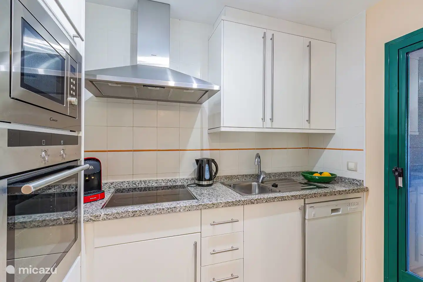 Küche mit diversen Einrichtungen wie Backofen, Mikrowelle, Espressomaschine, Wasserkocher