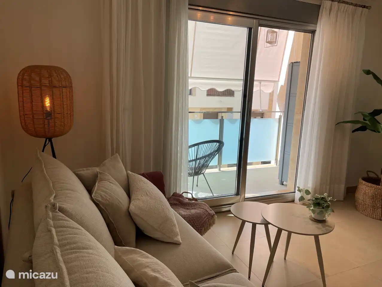 Séjour avec coin salon et portes coulissantes donnant sur un balcon avec des sièges.