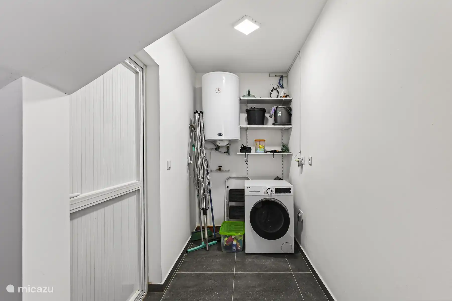 Praktische wasruimte met wasmachine, boiler en extra opbergruimte.