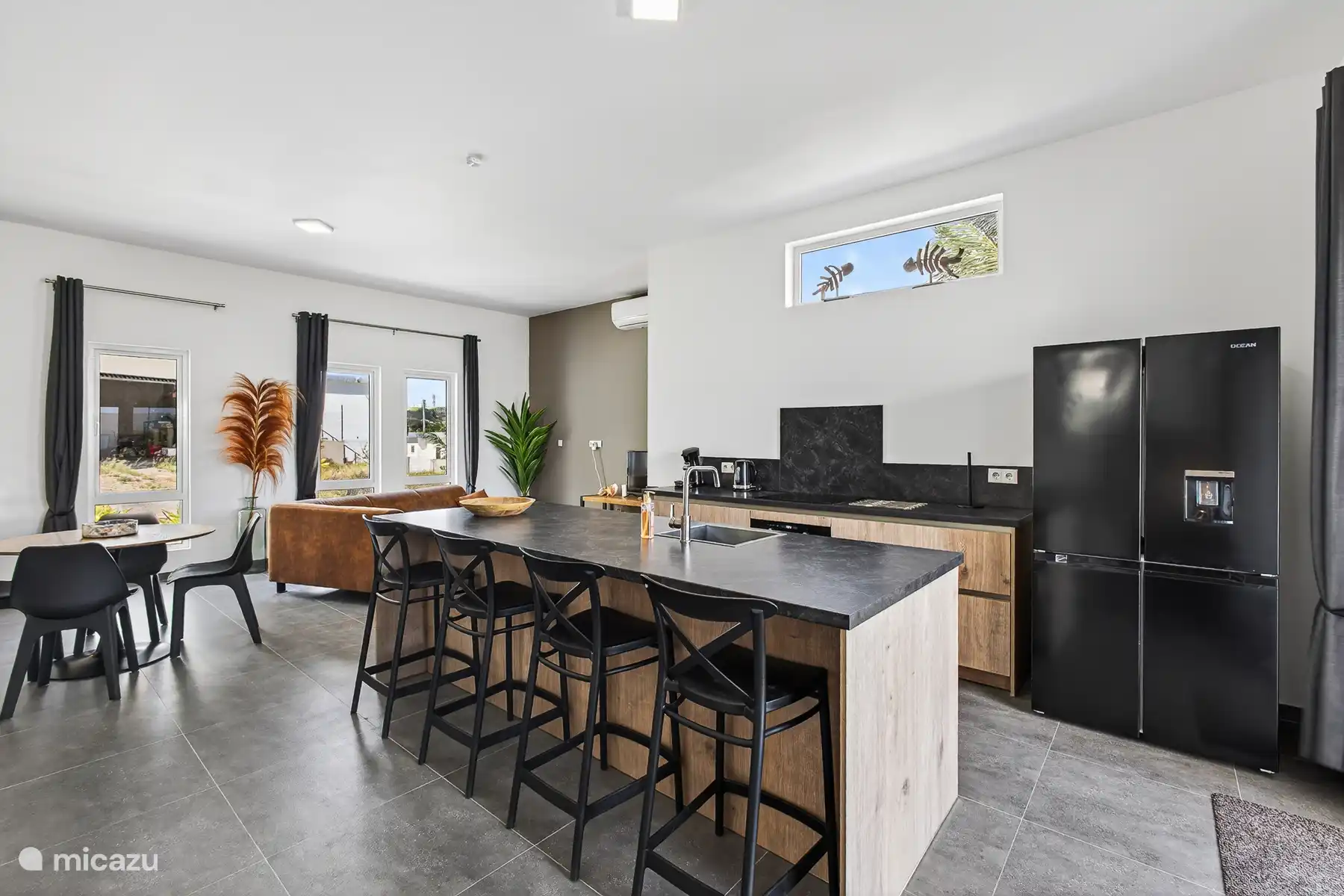 Ruime open keuken en eetruimte met kookeiland, barstoelen en moderne apparatuur.