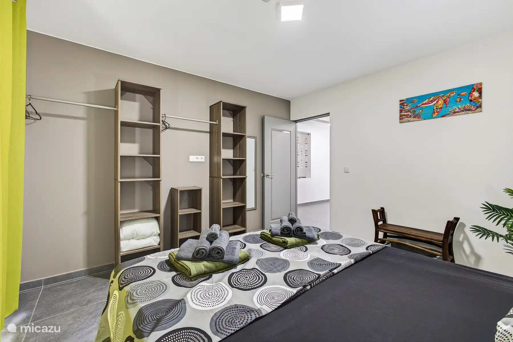 Slaapkamer met tweepersoonsbed en ruime open kastenwand.