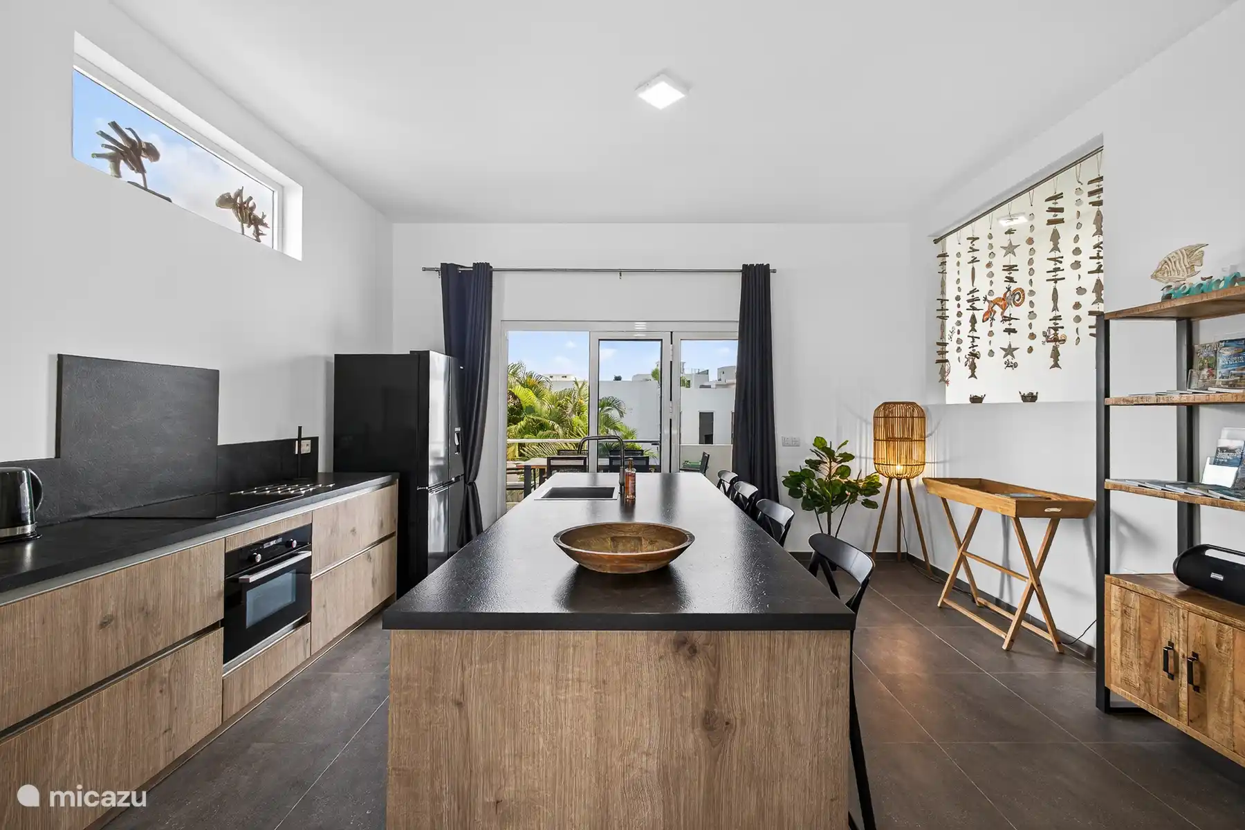 Luxe open keuken met kookeiland, moderne apparatuur en directe toegang tot het terras.