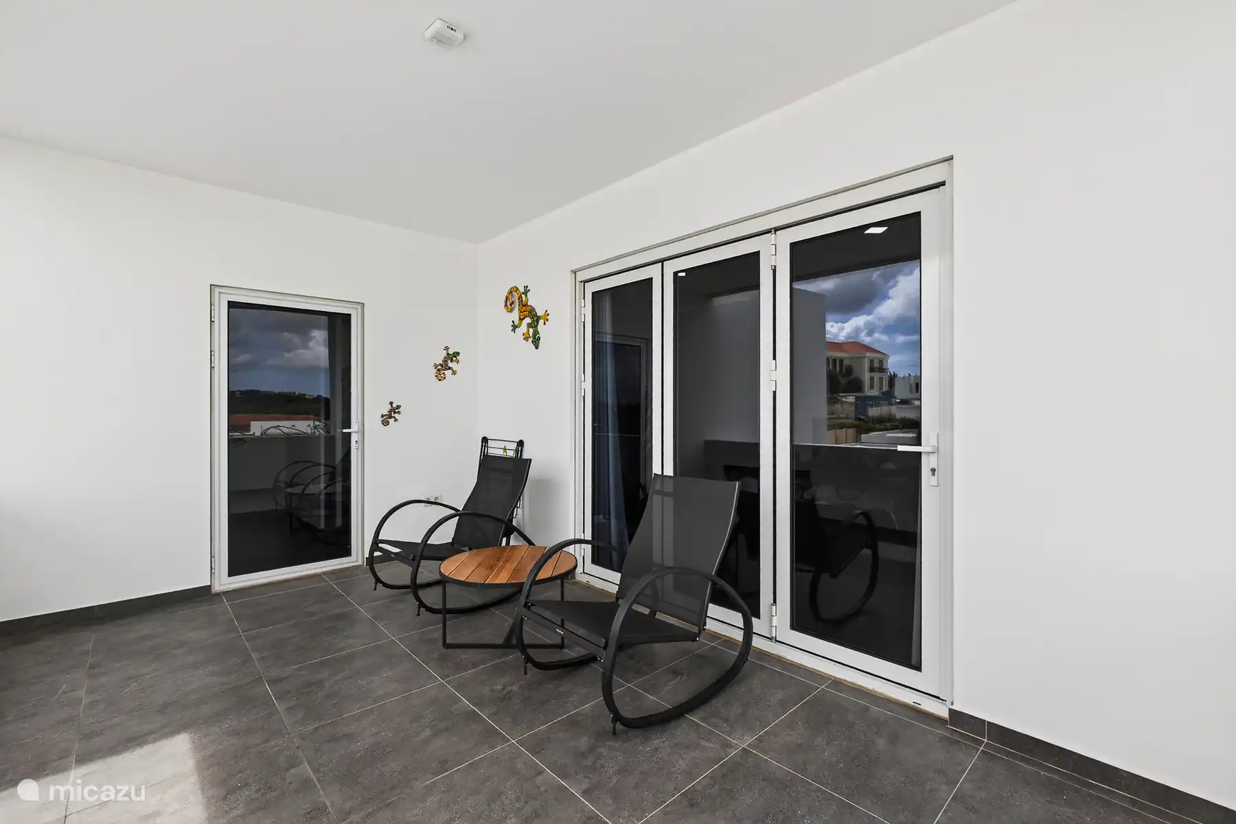 Overdekt balkon bij de master bedroom met zitje, ideaal om ’s ochtends of ’s avonds buiten te ontspannen.