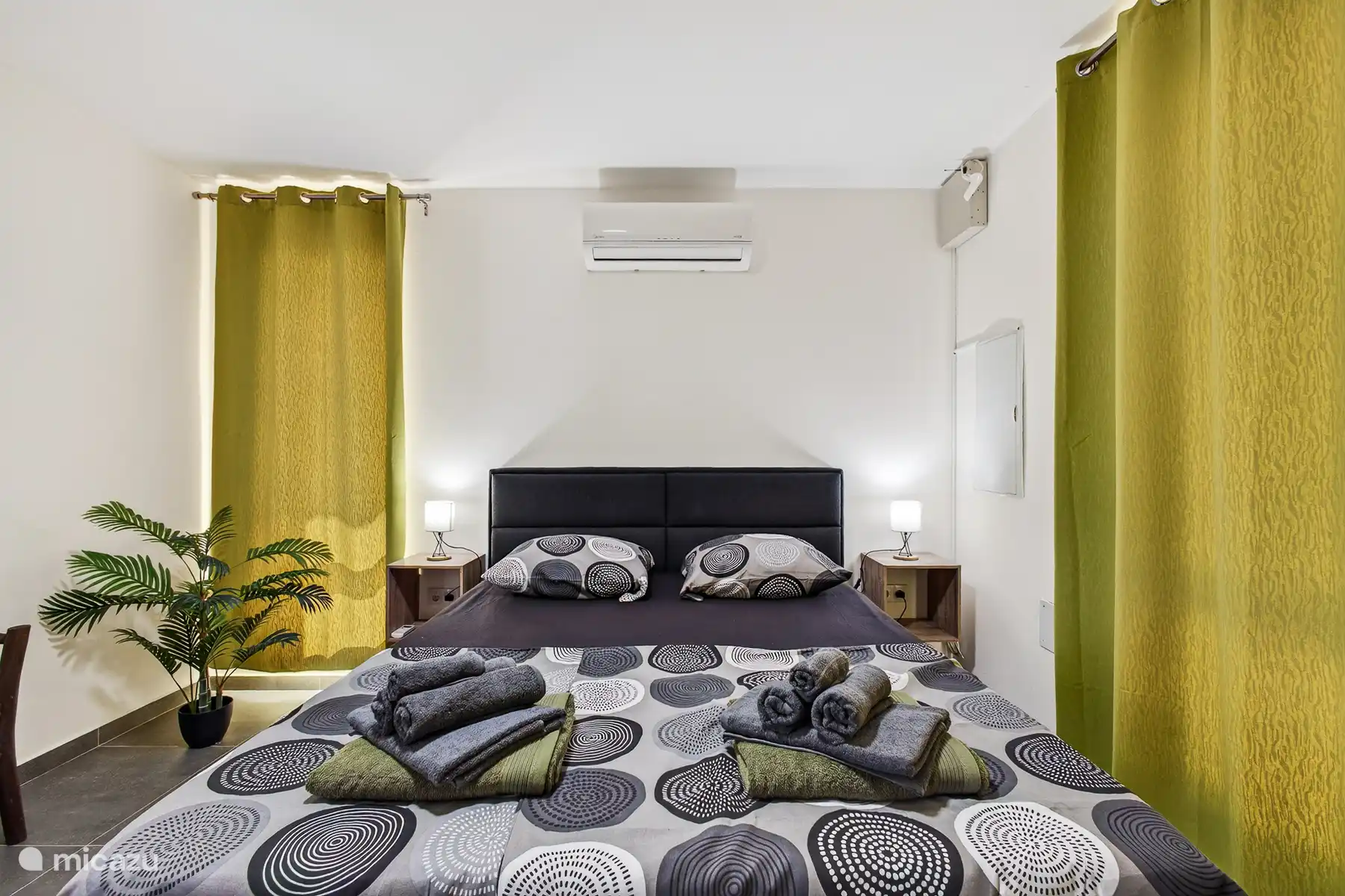 Comfortabele slaapkamer met tweepersoonsbed, airconditioning en nachtkastjes.