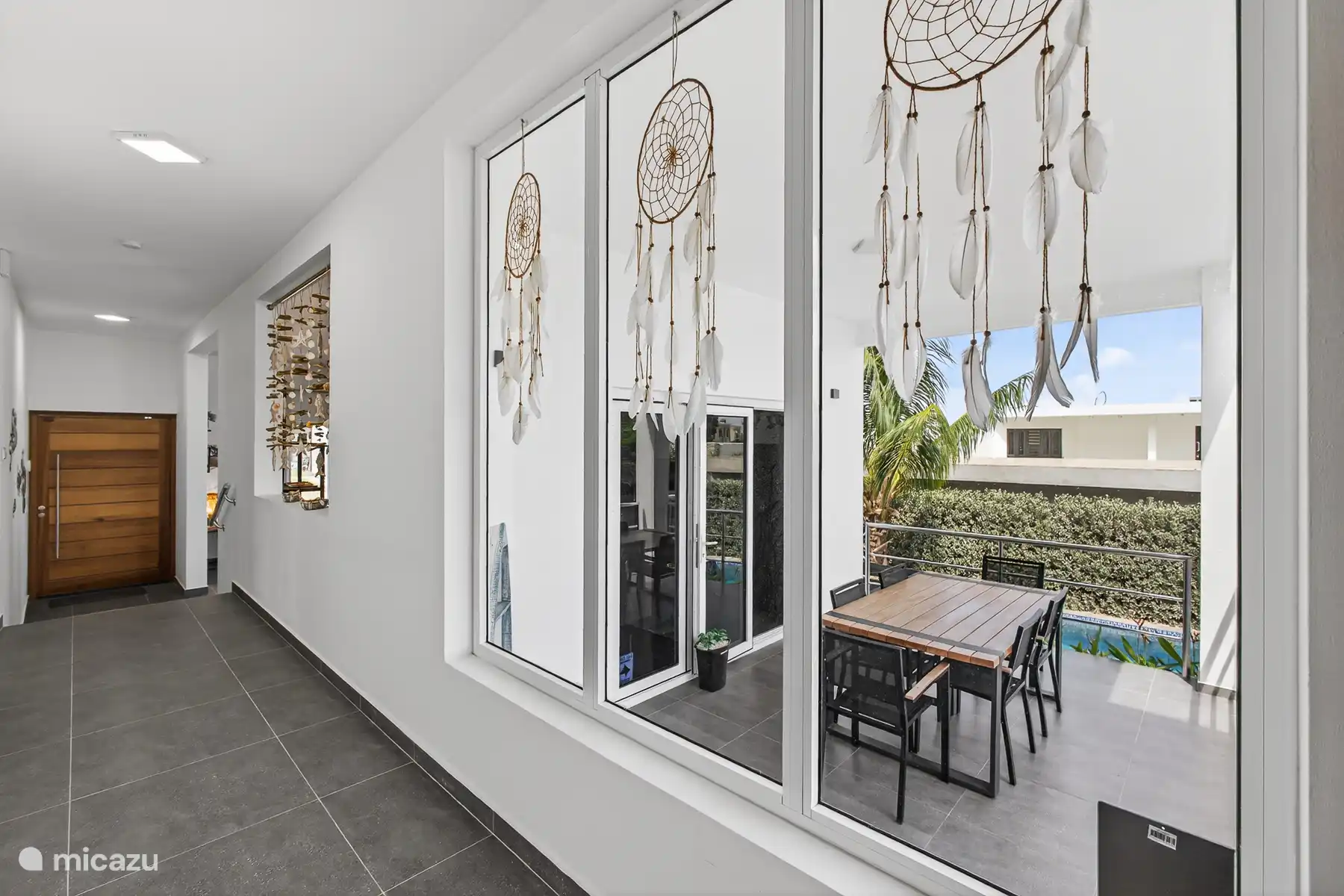 Overdekt terras met zitgedeelte en uitzicht op het zwembad.