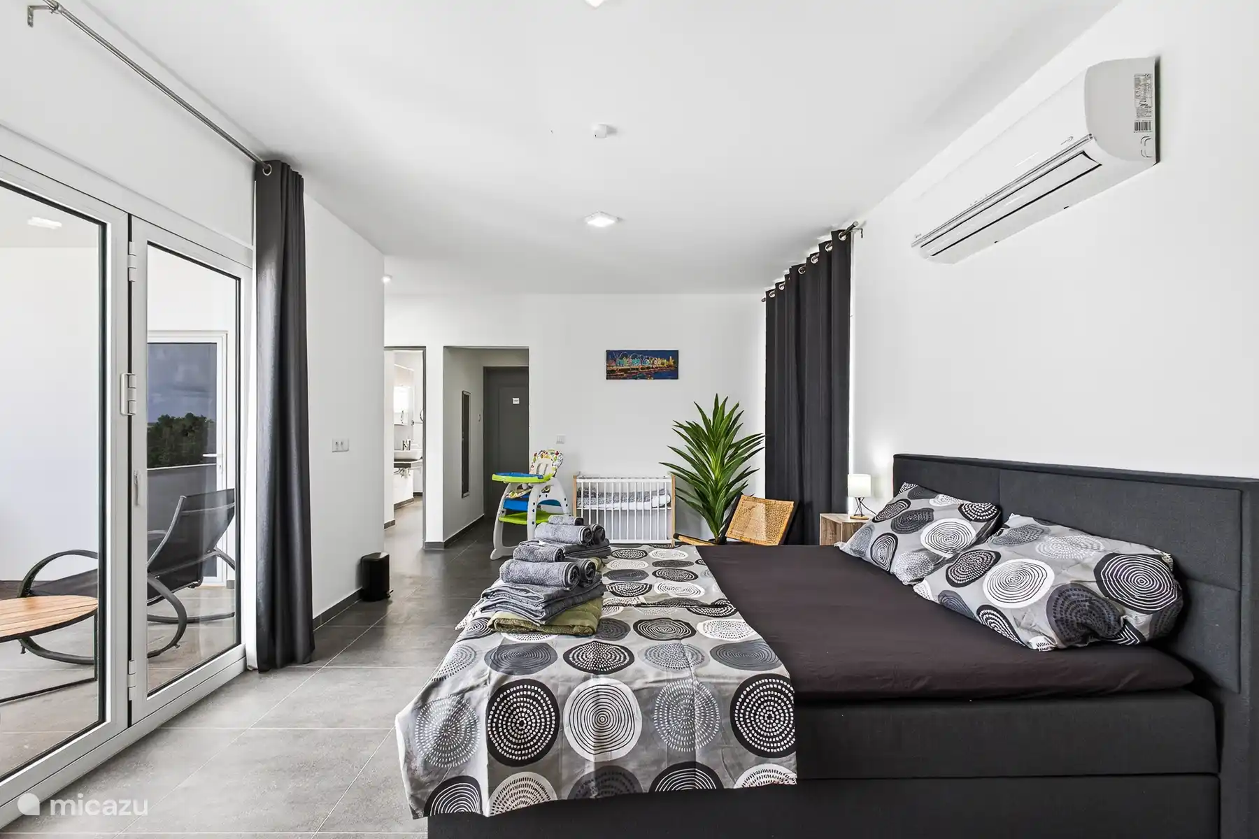 Ruime master bedroom met tweepersoonsbed, airconditioning en directe toegang tot het balkon.