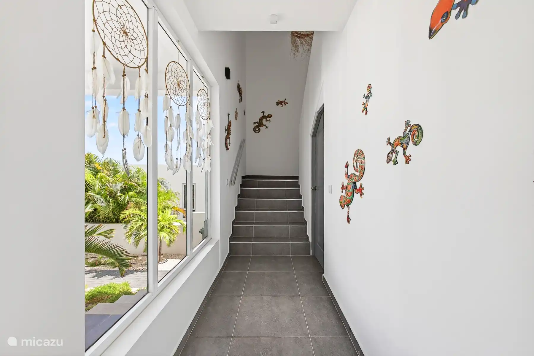 Lichte hal met trap naar de verdieping, sfeervol ingericht met decoratieve details.