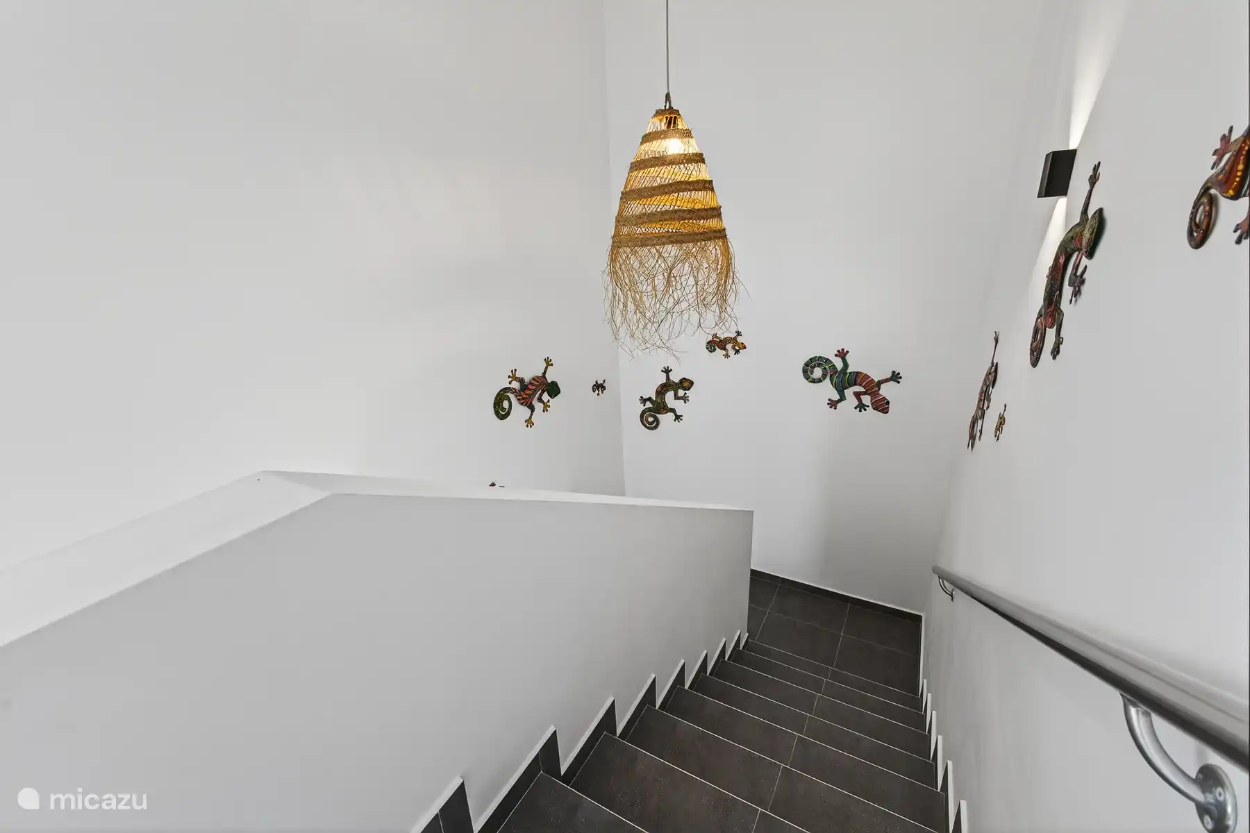 Trap naar de verdieping met decoratieve wanddetails en veel licht.