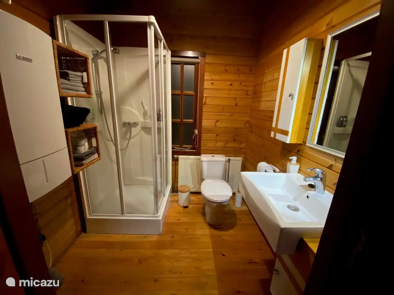 Badkamer met toilet, douche en ruime wastafel en opbergkastjes.