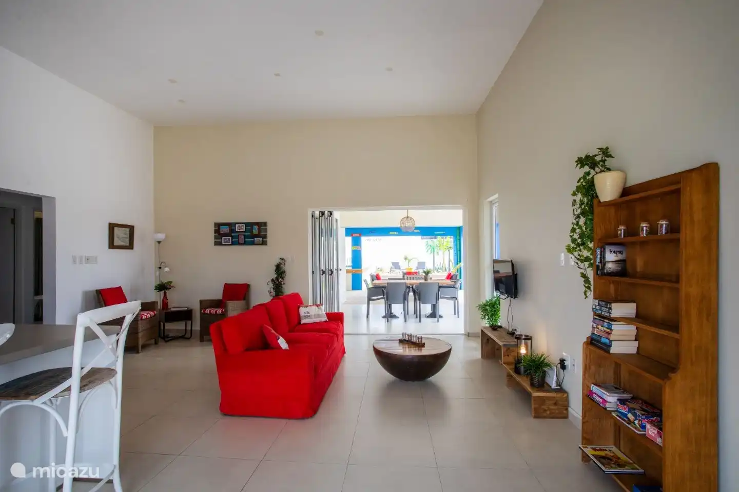 Das gemütliche Wohnzimmer mit Leseecke, Bücherregal, Fernseher und offener Küche. mit Blick auf die überdachte Terrasse und den Garten.