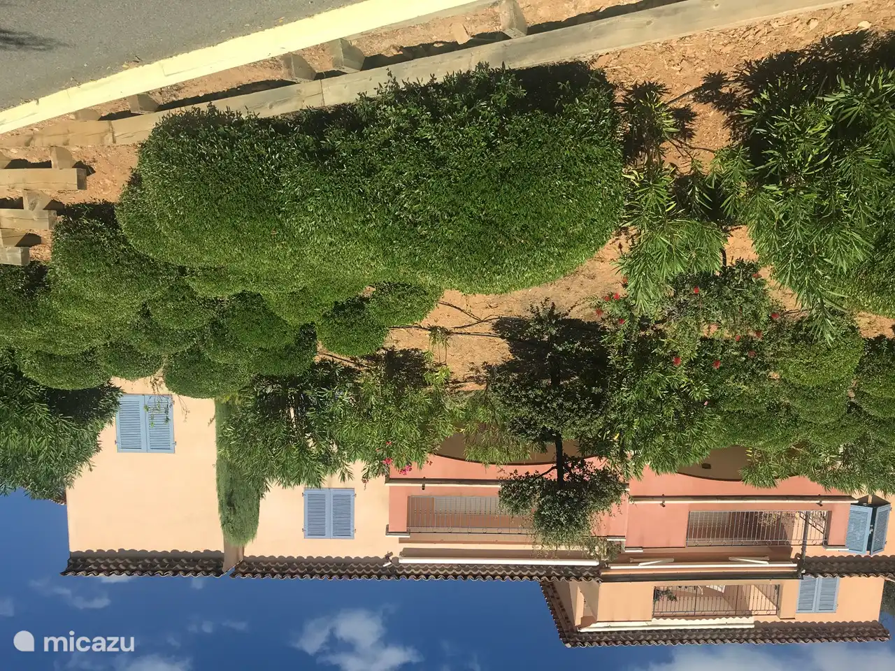 Die rechte Wohnung mit Terrasse und daneben blauen Fensterläden verläuft über die Ecke und befindet sich im 1. Stock