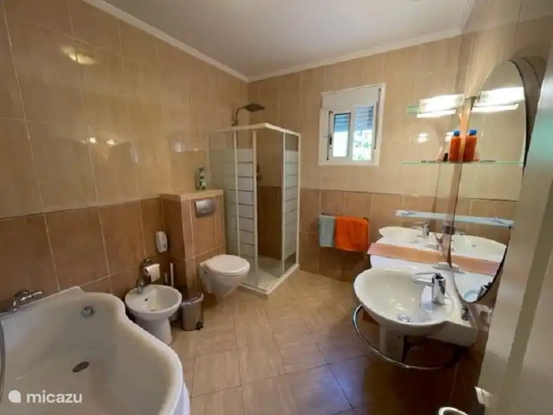 Salle de bain avec double lavabo, douche, baignoire et bidet. 