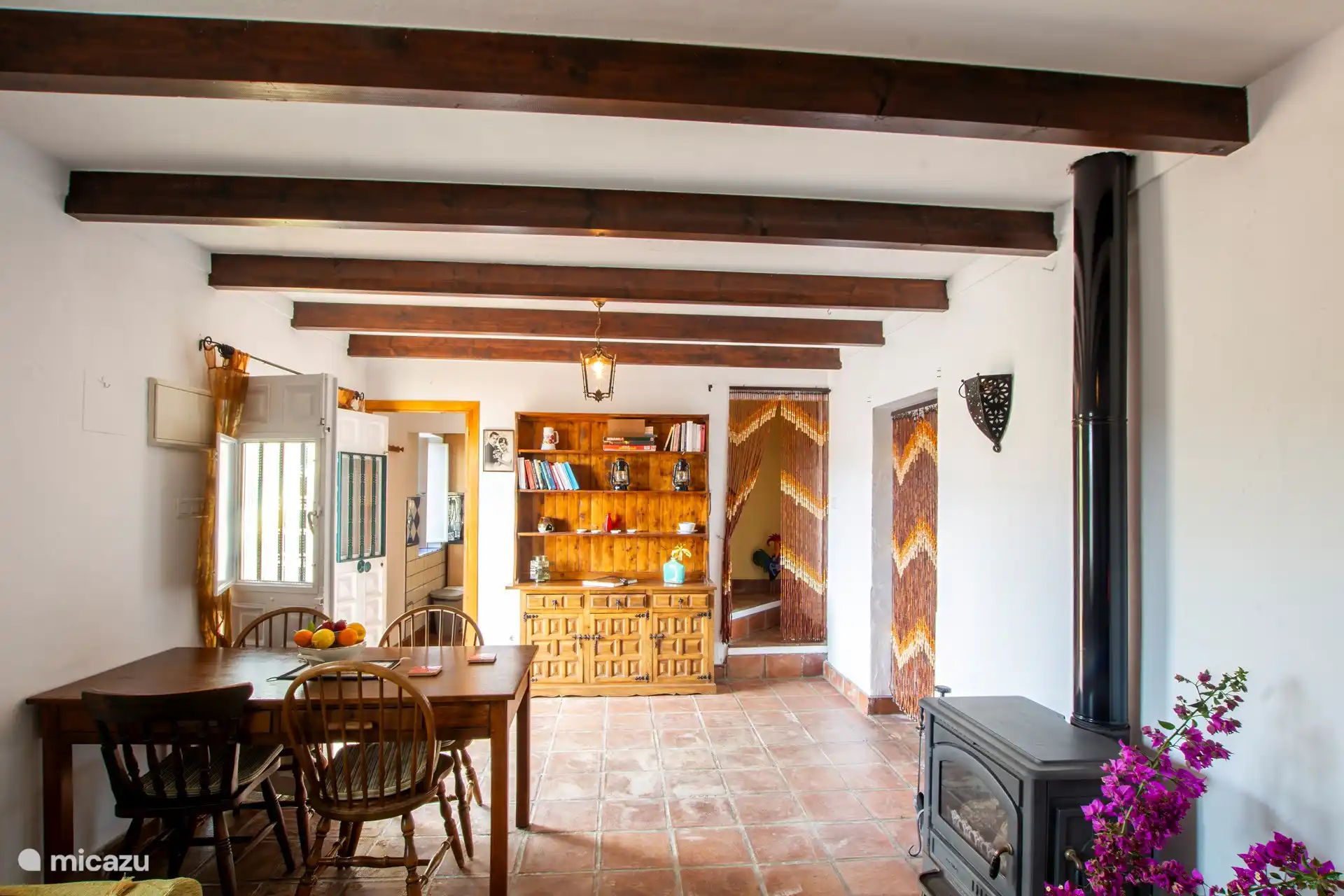 Eethoek met houtkachel. Leesvoer en spelletjes liggen voor je klaar.