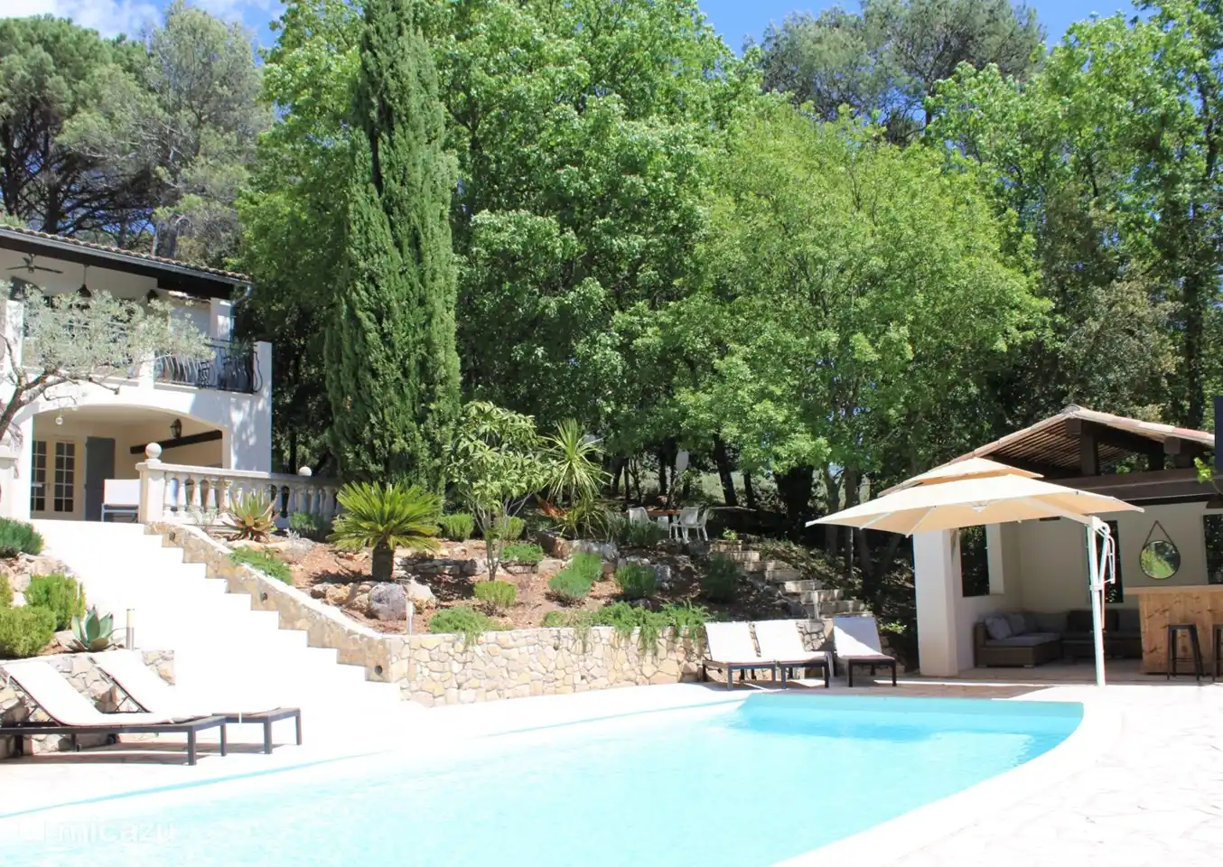 swimming pool with plenty of sunbeds, a large parasol and the pool house for sufficient shade